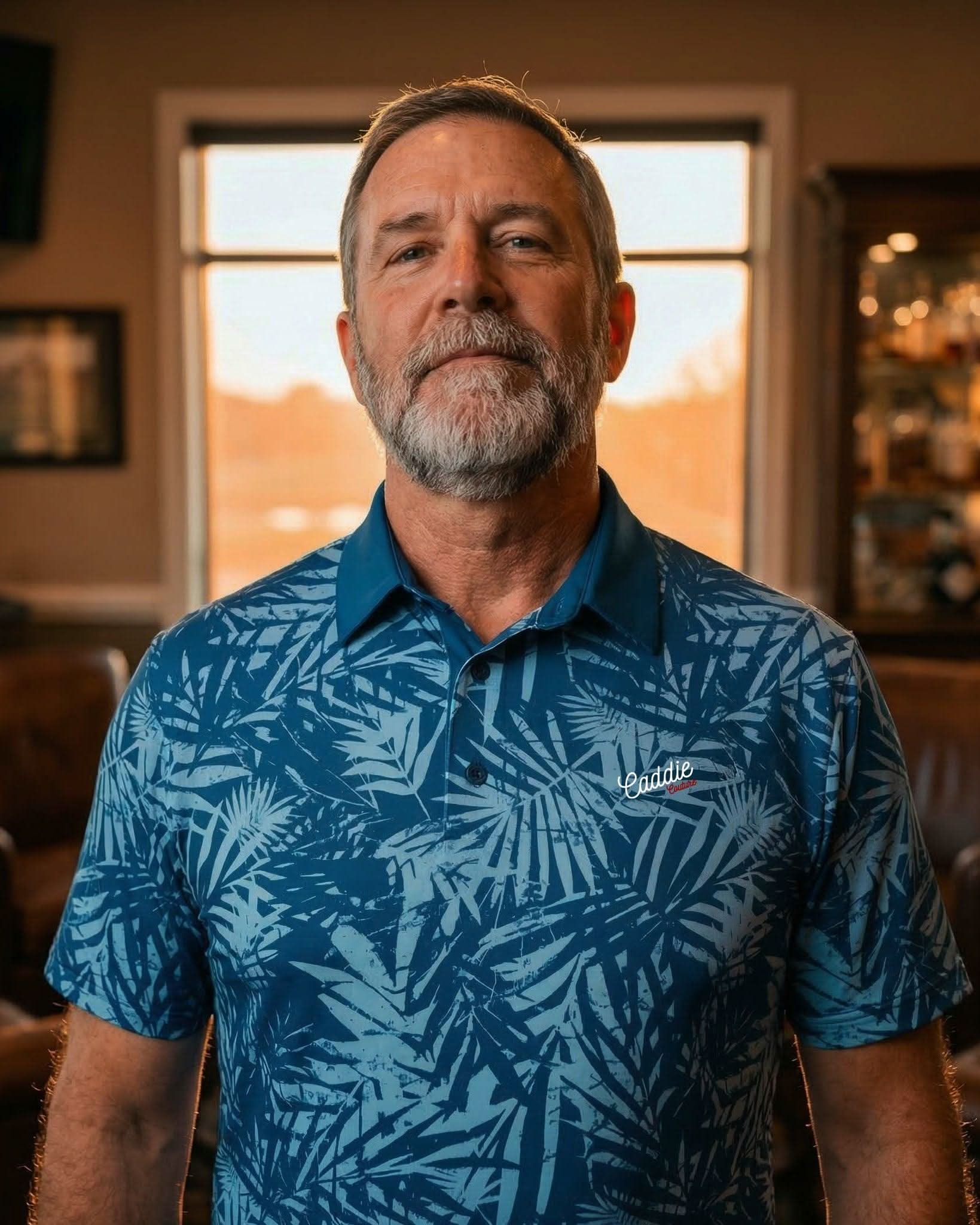 Man wearing a blue patterned shirt in an indoor setting with warm lighting
