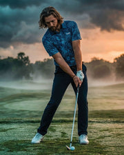 Man playing golf on a misty golf course with a dramatic sky.