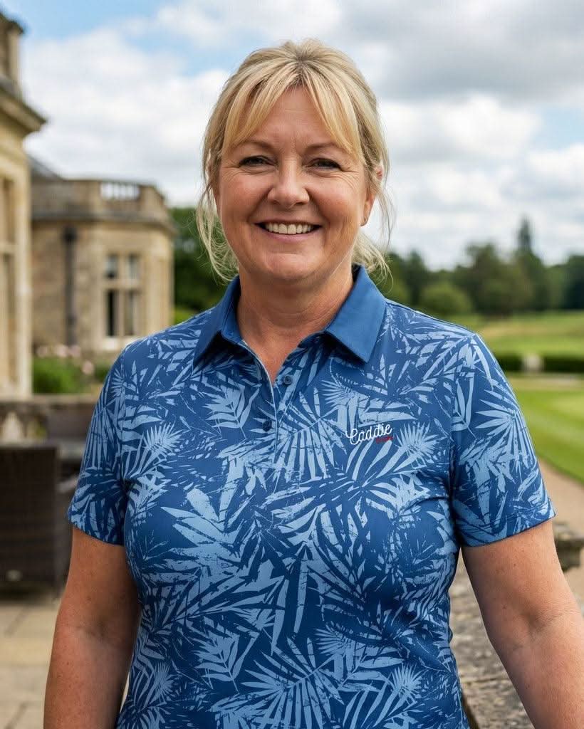 Woman wearing a blue patterned shirt standing in front of a building with greenery