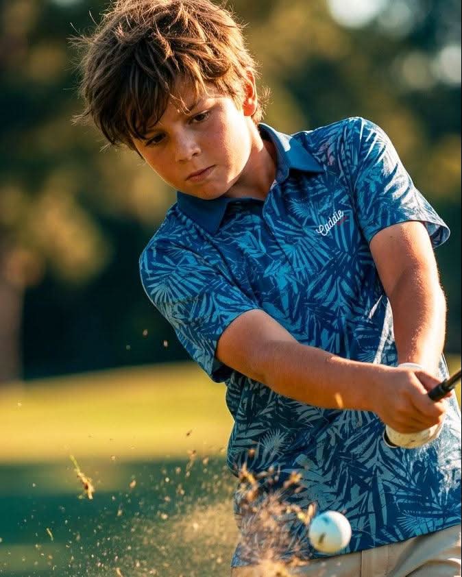 Young boy playing golf on a green course with trees in the background