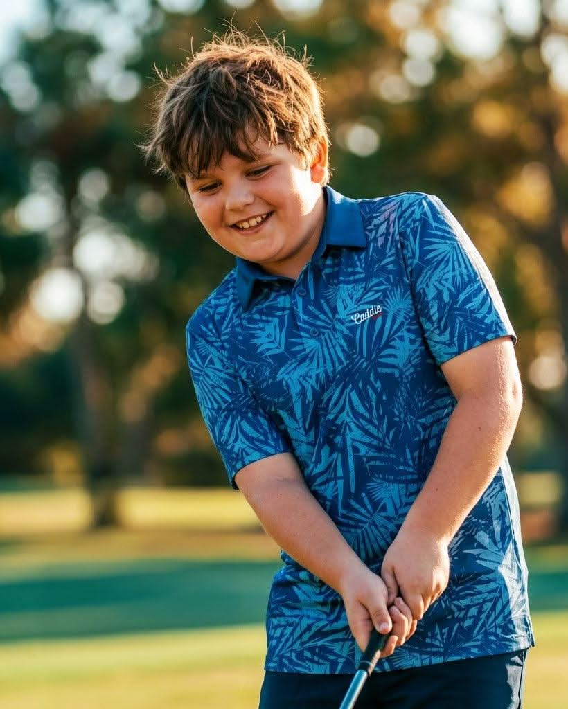 Child in a blue patterned shirt holding a golf club on a golf course