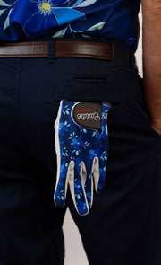 Blue floral-patterned golf glove on a person wearing dark pants.