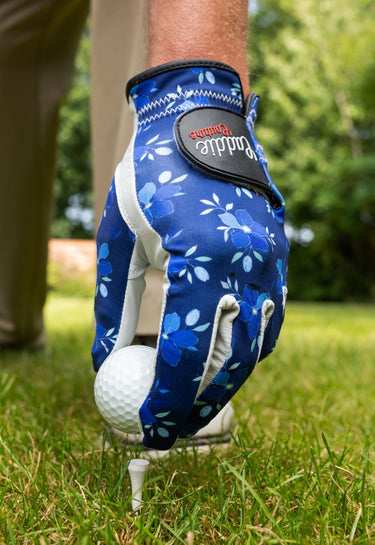 Blue floral golf glove on a golf ball with a blurred green background