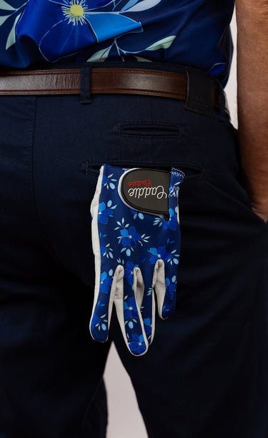 Blue floral-patterned golf glove on a person wearing dark pants.