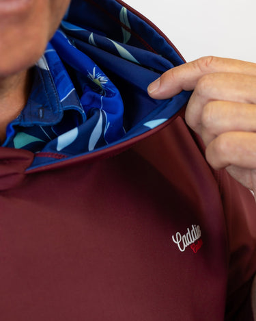 Person wearing a maroon golf hoodie with a blue lining, featuring a visible brand logo.