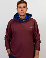 Man wearing a maroon golf hoodie with a blue lining on a plain background