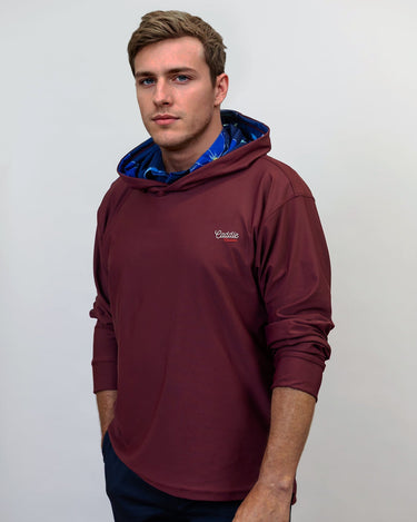 Man wearing a maroon golf hoodie with a logo on a white background