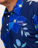 Navy blue golf shirt with floral design and 'Caddie Couture' logo on a white background
