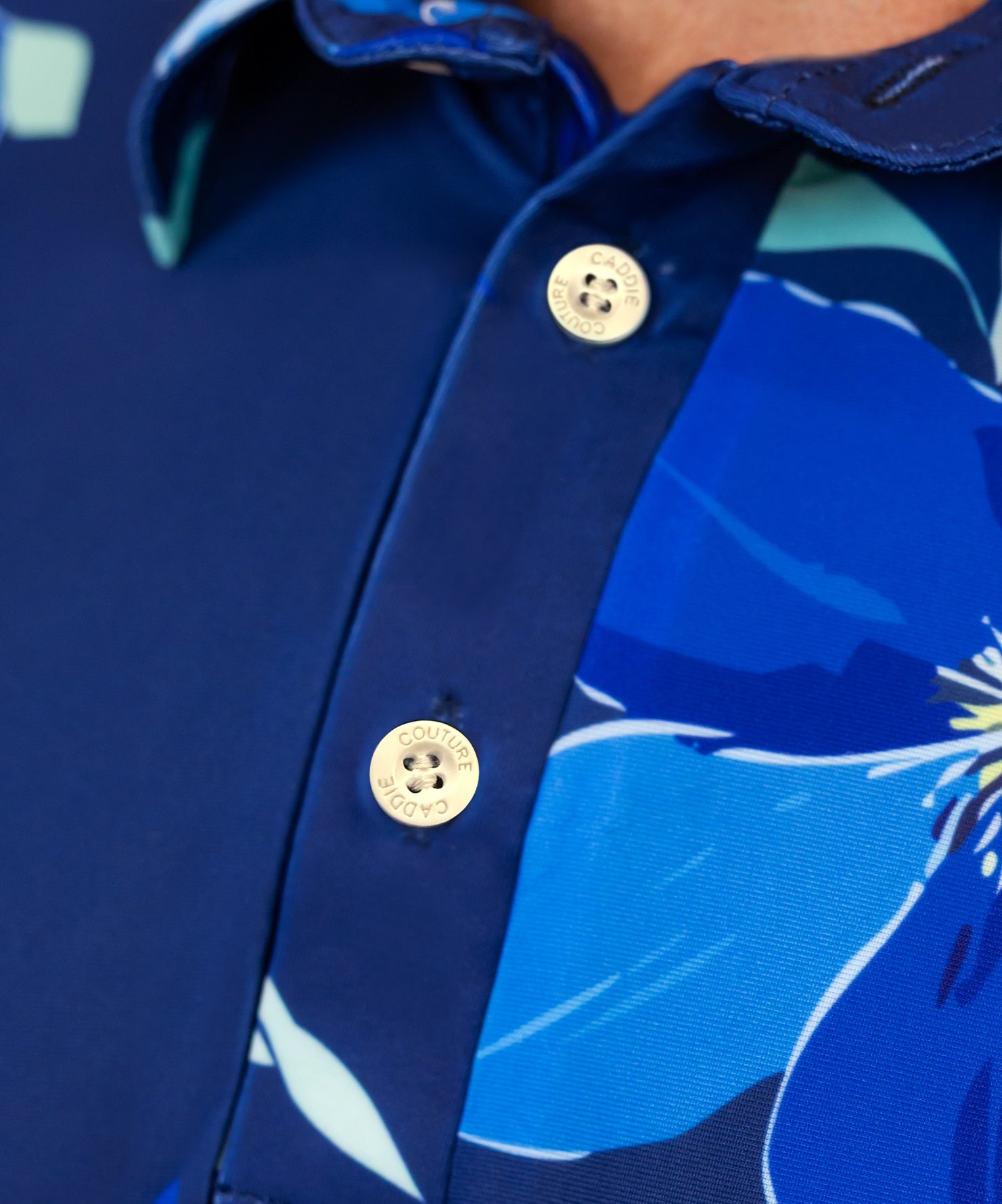 Close-up of a blue golf shirt with floral patterns and caddie couture buttons