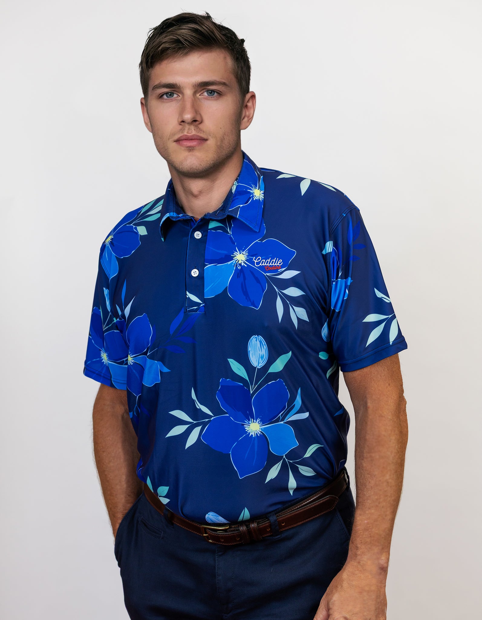 Man wearing a blue floral patterned golf shirt on a plain background