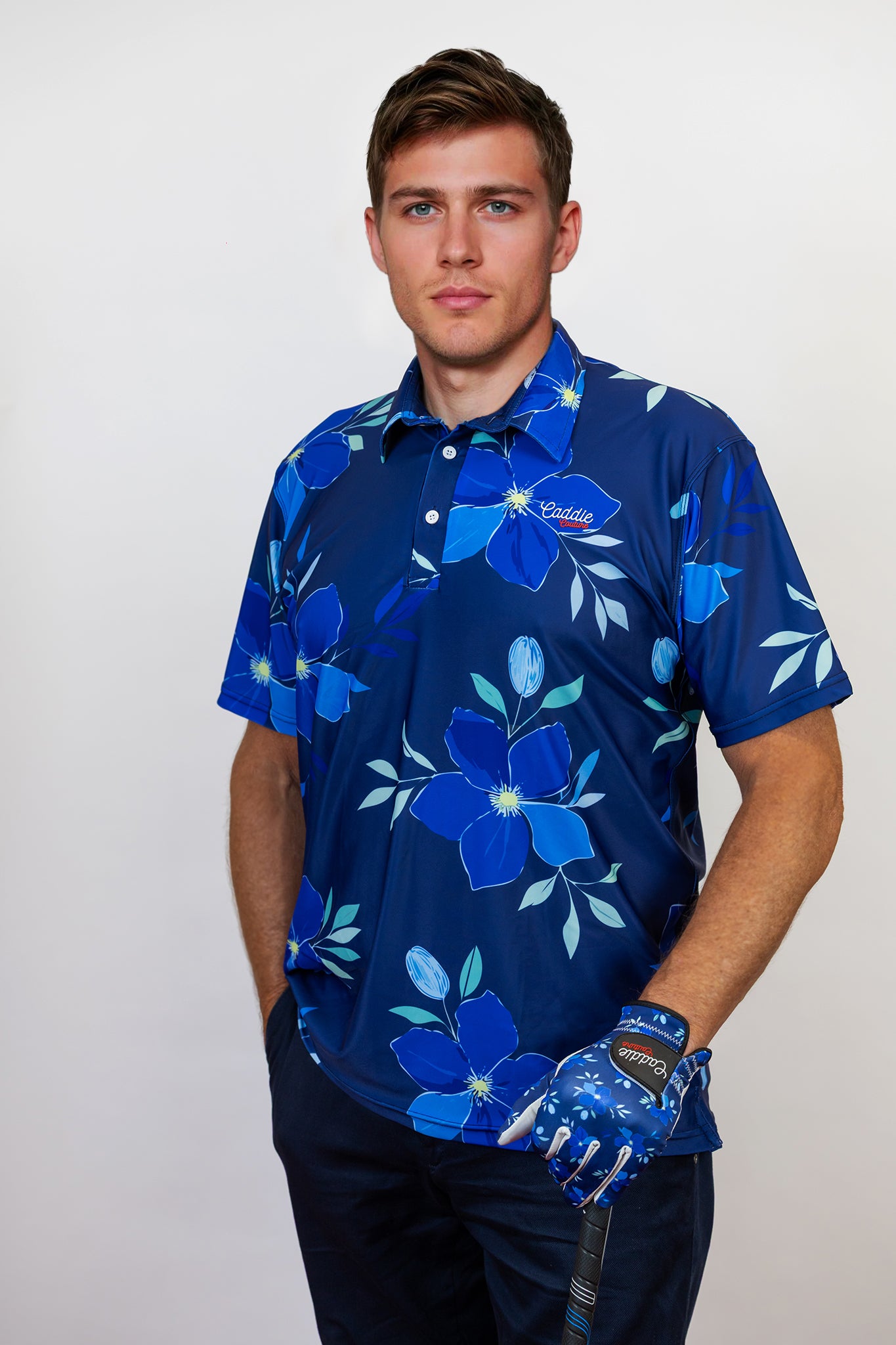 Man wearing a blue floral patterned golf shirt with a golf club on a white background