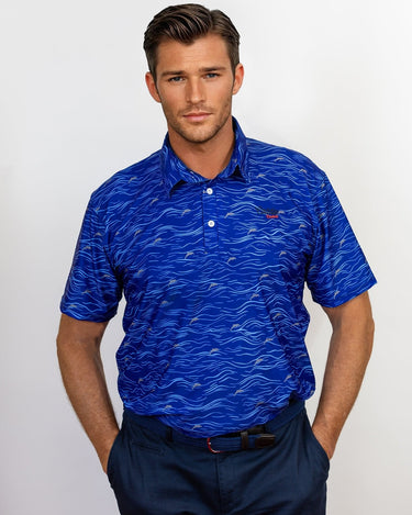 Man wearing a blue patterned golf polo shirt with a visible caddie couture logo on a white background