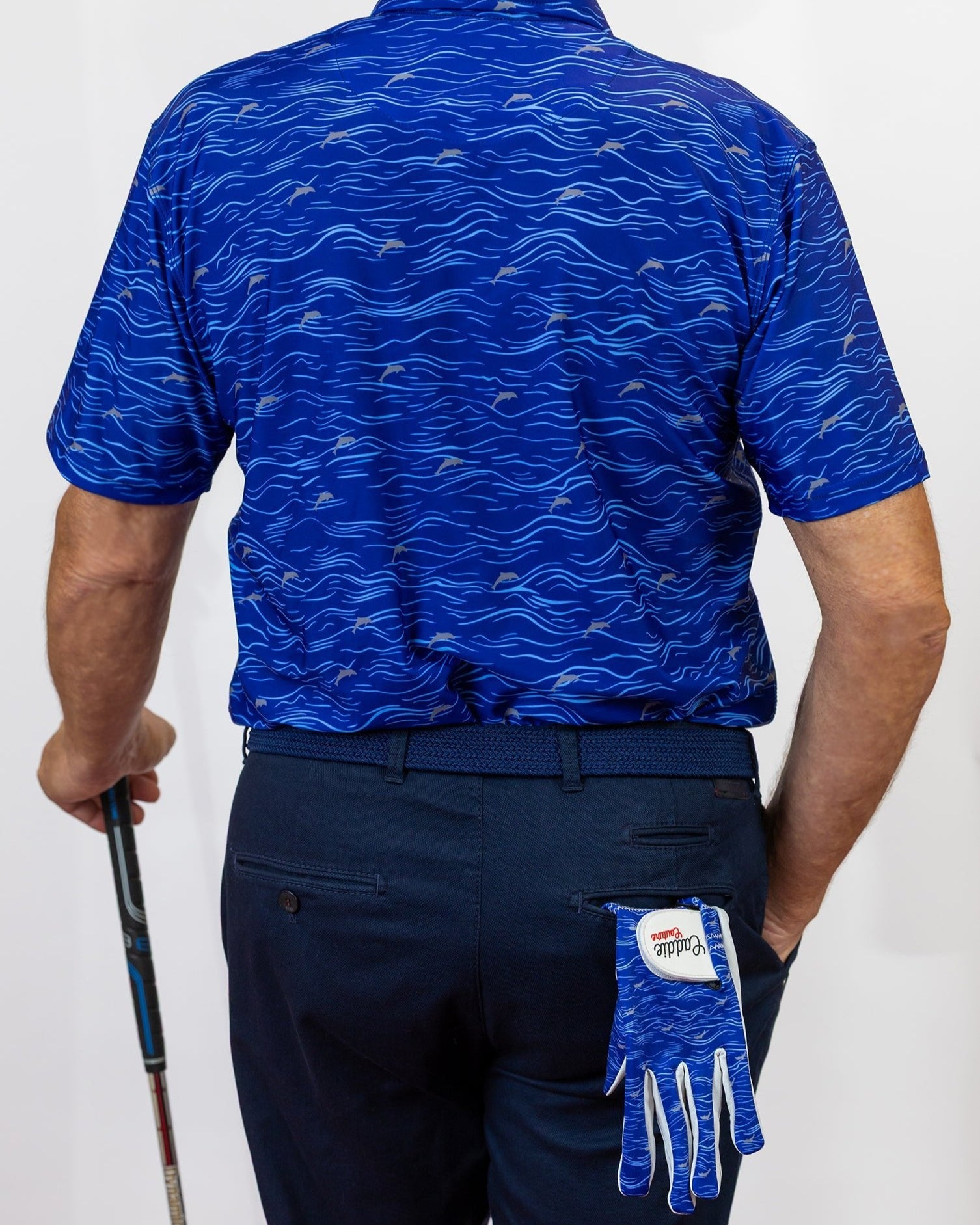Person wearing a blue patterned golf shirt and navy pants, holding a golf club, with a blue glove on a white background.