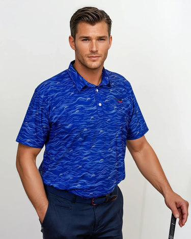 Man wearing a blue patterned golf polo shirt and dark pants, holding a golf club.