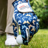 Golf glove with butterfly pattern holding a golf ball on grass