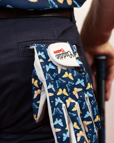 Glove with butterfly pattern held by a person wearing a matching outfit.