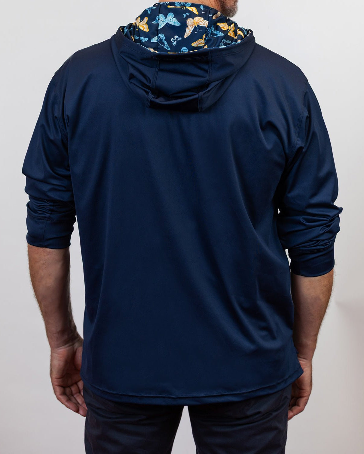 Person wearing a navy blue hoodie with a butterfly pattern on the hood against a white background