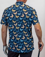 Person wearing a blue golf polo with butterfly pattern holding a golf club.