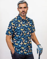 Man wearing a blue Golf Polo with butterfly pattern and holding a golf club on a white background