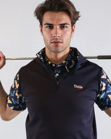 Man wearing a navy blue vest over a patterned shirt, holding a golf club.