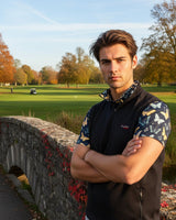 Man standing on a golf course with a stone bridge in the background