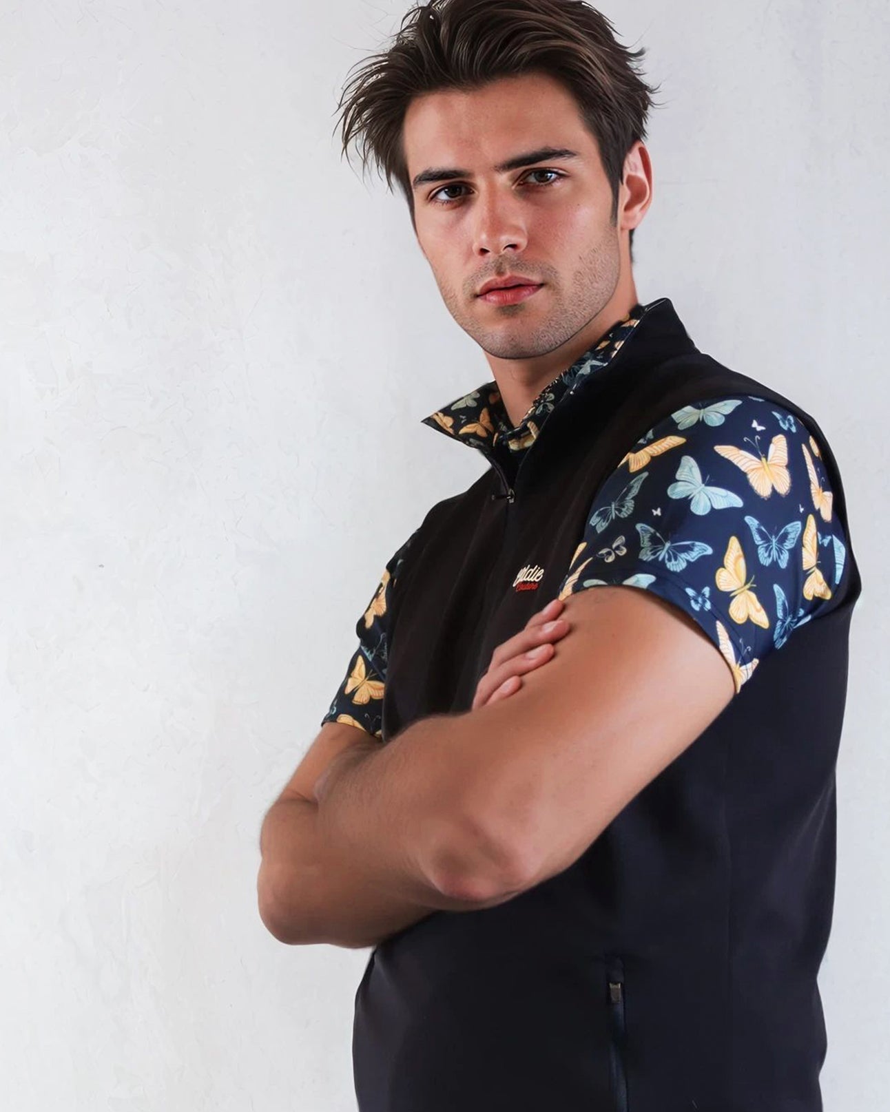 Man wearing a navy golf vest with butterfly pattern against a white background