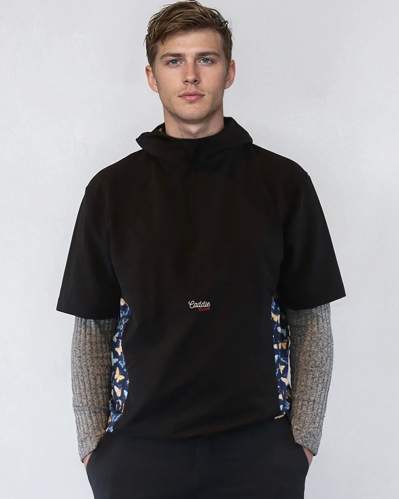Man wearing a black windbreaker shirt with patterned sides against a white background