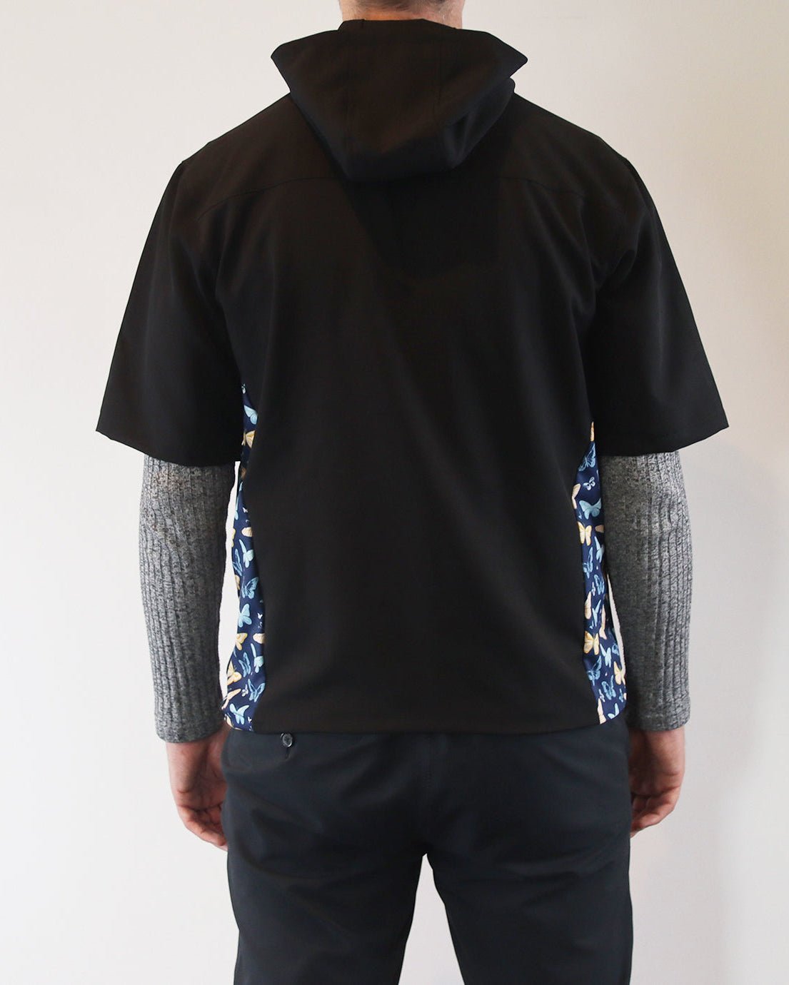 Person wearing a black windbreaker shirt with floral sides against a plain background