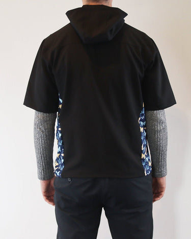 Person wearing a black windbreaker shirt with floral sides against a plain background