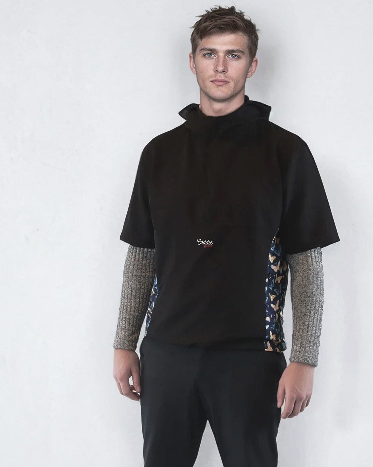 Man wearing a black windbreaker shirt with patterned sides on a white background