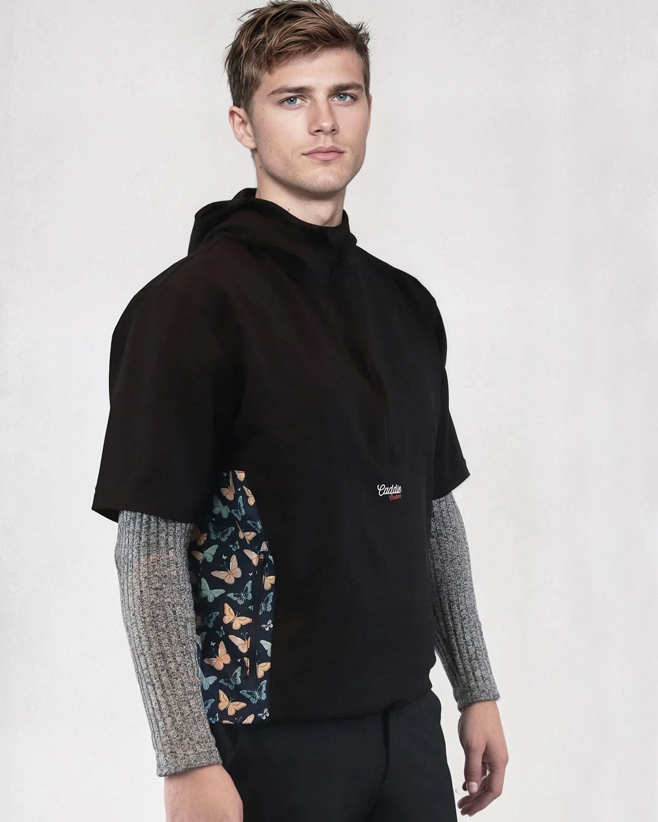 Man wearing a black windbreaker shirt with patterned sides on a white background