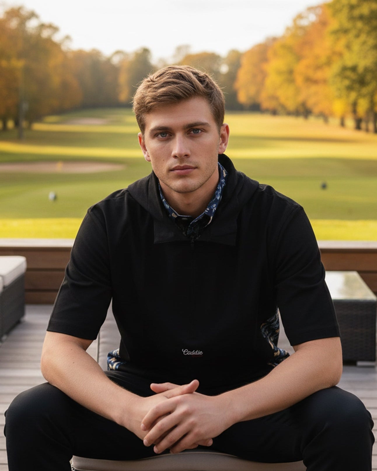 Man sitting outdoors with a scenic background of trees and grass.