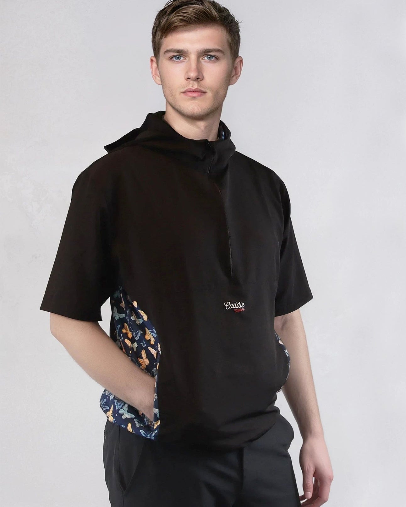 Person wearing a black windbreaker jacket with a butterfly pattern on the sides