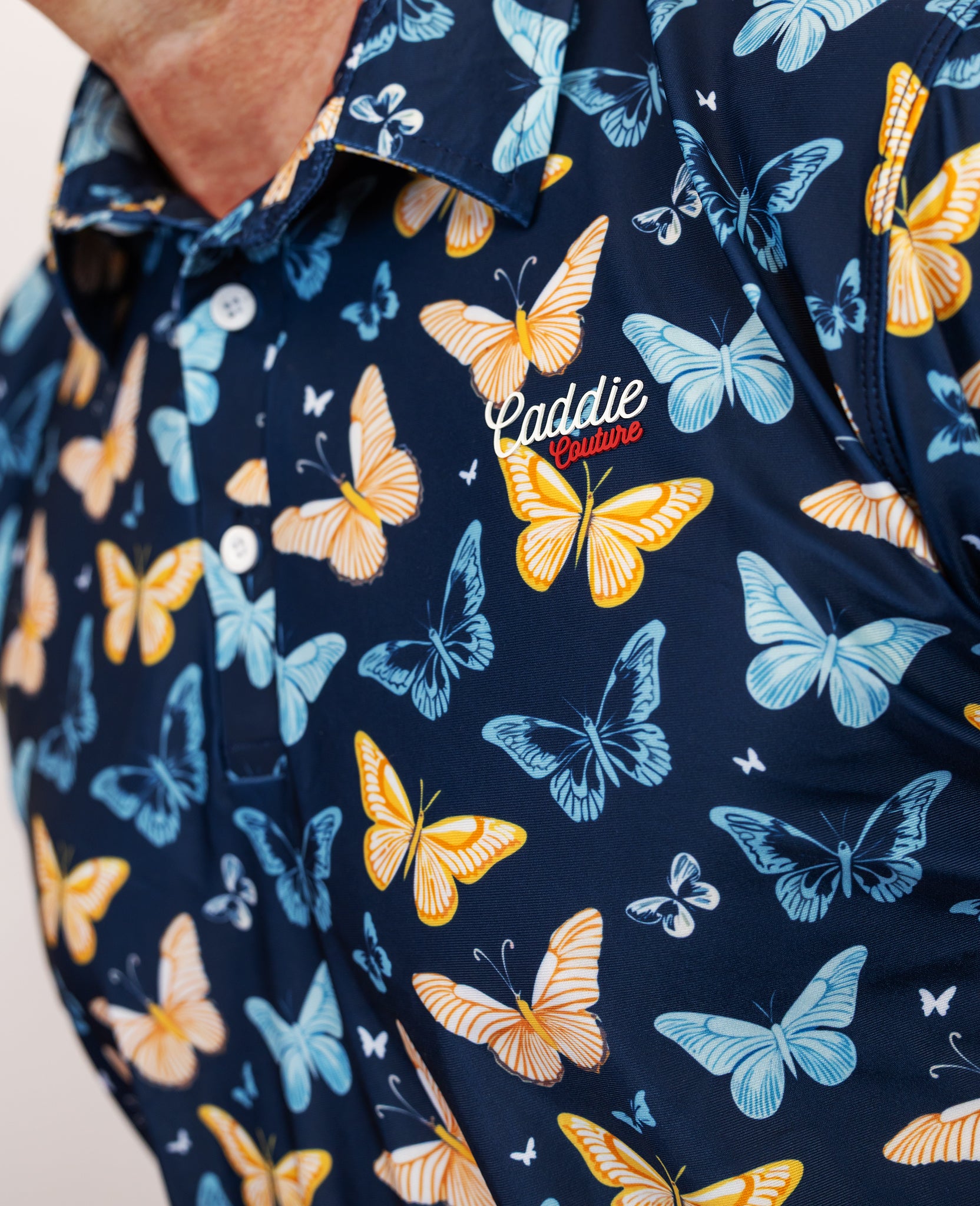 Navy Golf Polo with colorful butterfly pattern and 'Caddie Couture' branding.