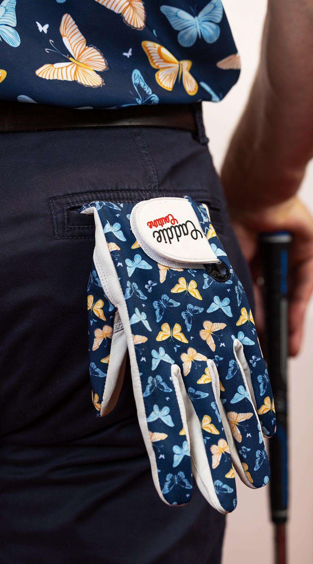 Glove with butterfly pattern held by a person wearing a matching outfit.