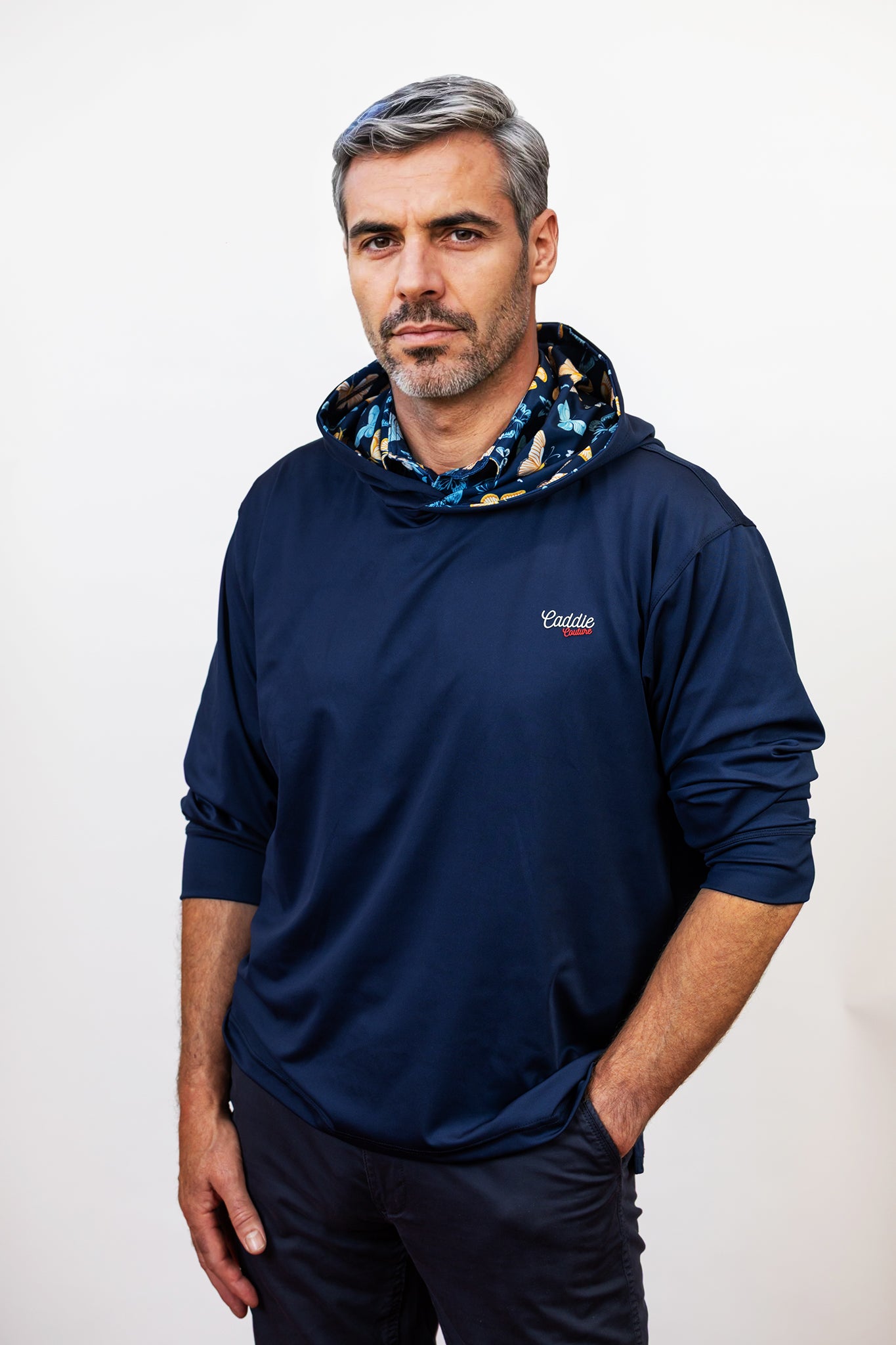Man wearing a navy blue hoodie with a patterned hood against a white background