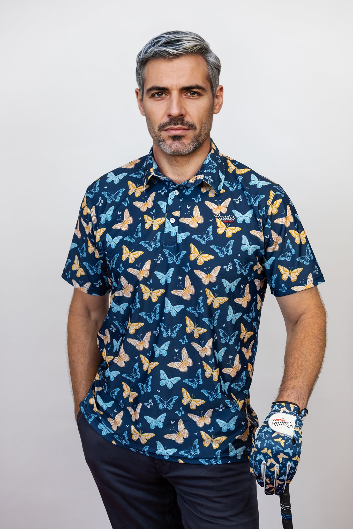 Man wearing a blue butterfly pattern Golf Polo and holding a golf club.