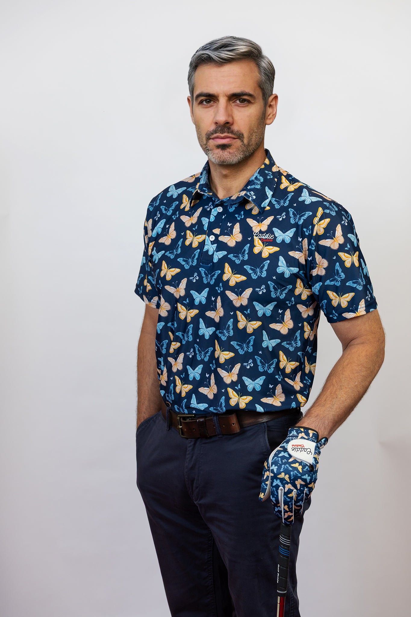 Male Model Wearing Butterfly Patter Golf Polo with a matching Butterfly Golf Glove. Model is posing with a Golf club in hand 