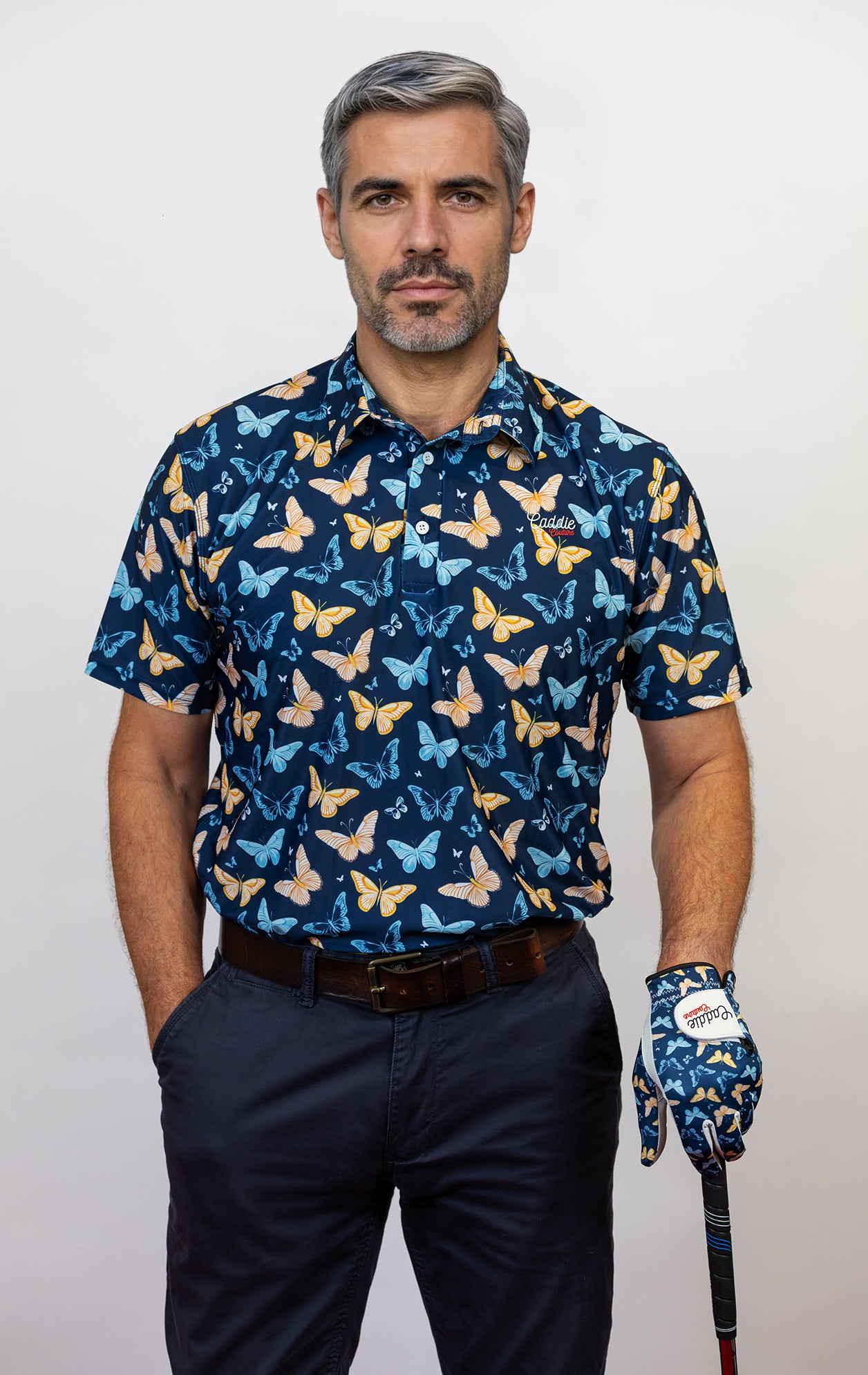 Man wearing a blue butterfly pattern shirt and glove, holding a golf club.