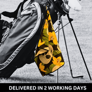 A golf towel with a camouflage pattern hanging on a golf bag, attached by a bag hook.