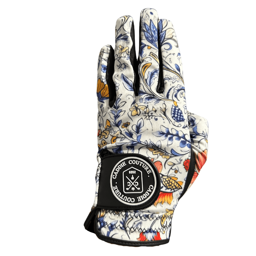 A multicolored floral-patterned golf glove with a black wrist strap and a logo on the back of the hand.