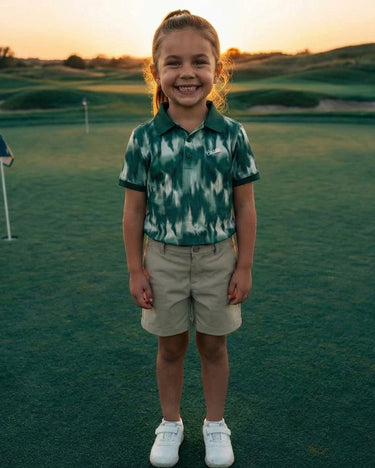 Child standing on a golf course with a sunset in the background