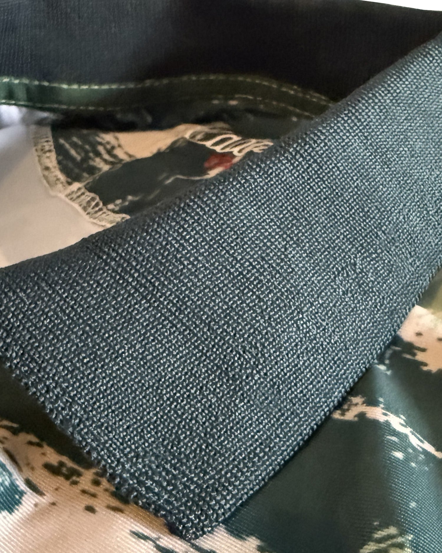 Close-up of a dark charcoal gray knit collar laid over a camouflage-patterned fabric background.