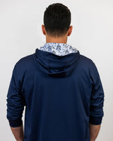 Person wearing a navy blue golf hoodie with a pattern inside on a white background