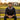 Man sitting on a wooden bench in a park with a building and trees in the background