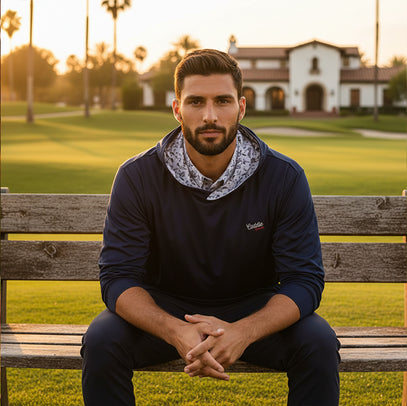Man sitting on a wooden bench in a park with a building and trees in the background