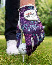Golf glove with floral pattern on a tee with a golf ball, on a grassy background