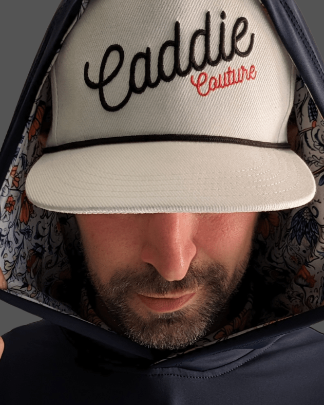 A male model wearing a navy blue hoodie with vintage floral print detailing on the hood.