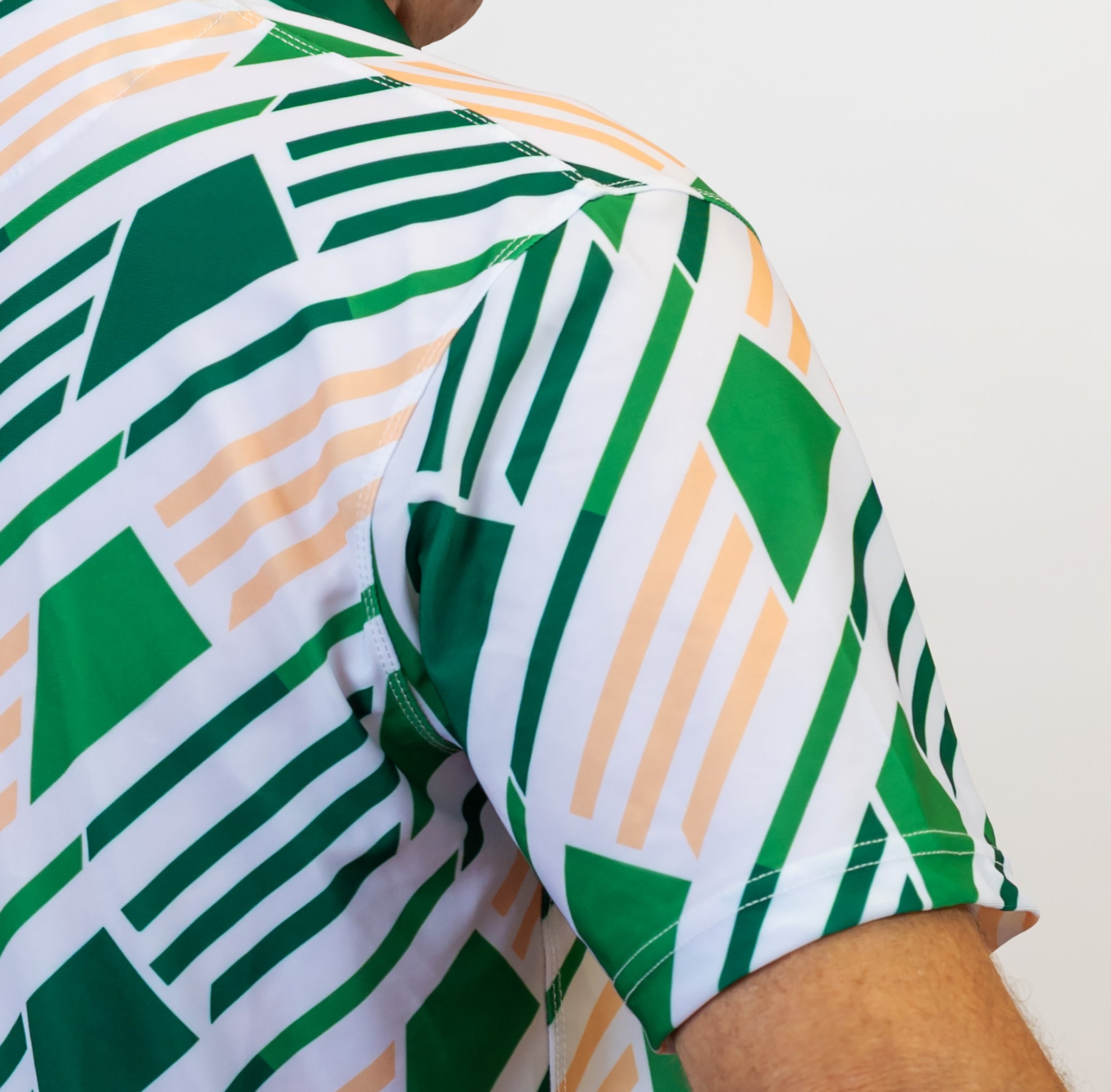 Close-up of a green and white geometric patterned golf shirt with a blurred background