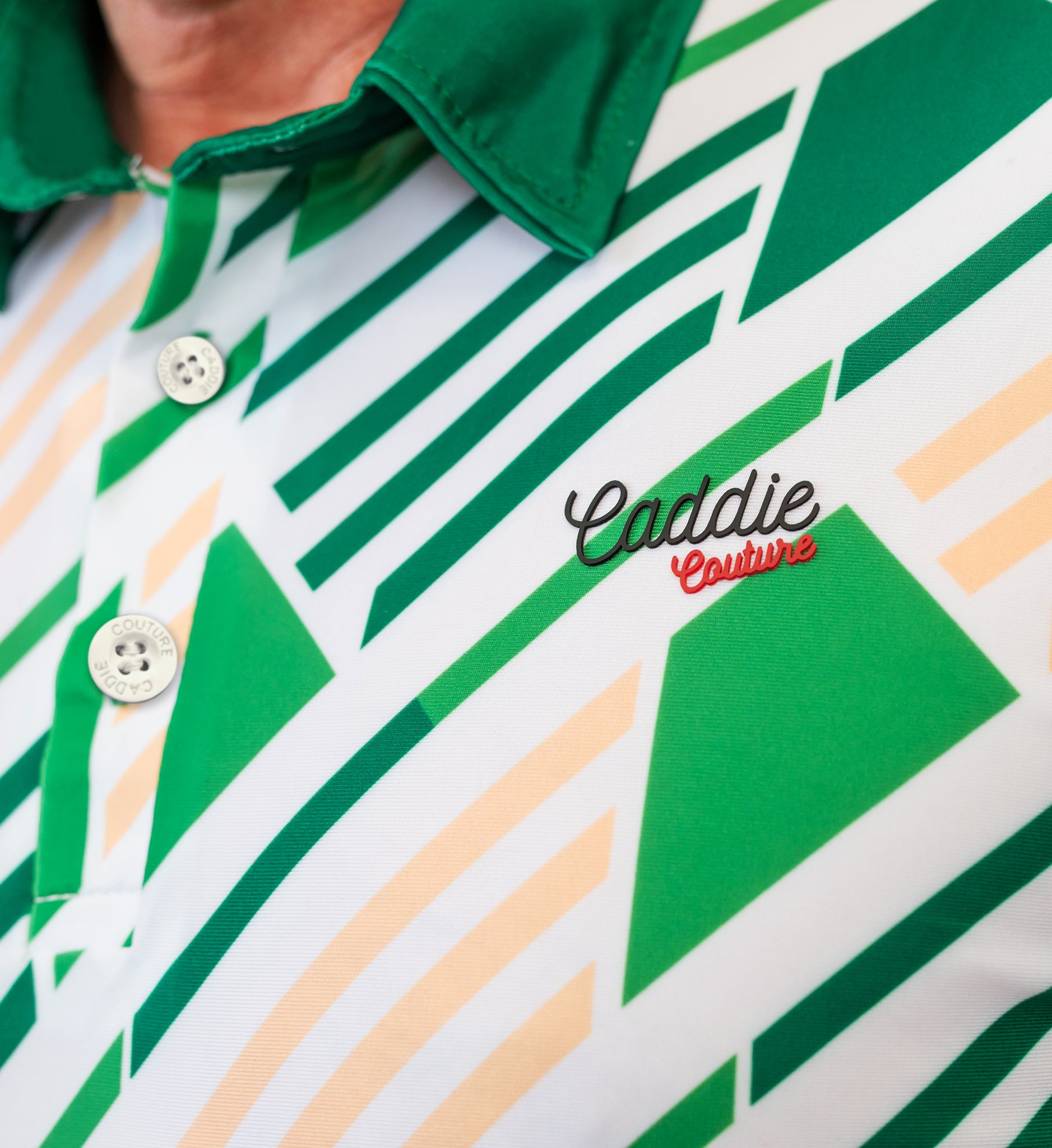 Close-up of a green and white patterned golf shirt with 'Caddie Couture' branding.
